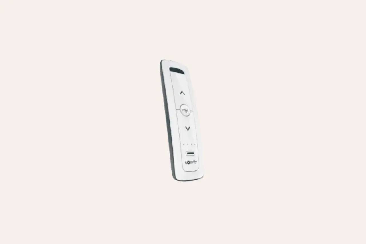 Une télécommande blanche moderne avec des boutons de contrôle et un logo "Somfy" en bas.